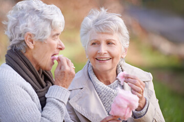 Senior women, eating and snack in nature with candy floss, together and relax on retirement...