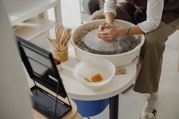 Close up of hands of professional potter molding pot shape on pottery wheel. Ceramics art concept