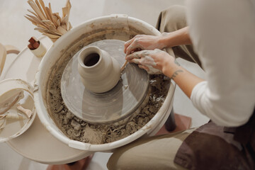 Close up of hands of professional potter molding pot shape on pottery wheel. Ceramics art concept