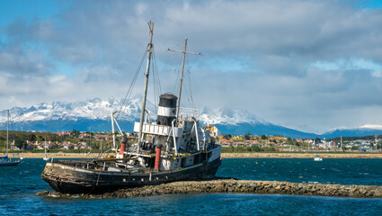 Naklejka premium Old fishing boat wreckage stranded on the shores of the port city of Ushuaia, Tierra del Fuego, Patagonia, Argentina