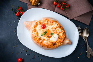 Georgian khachapuri with egg, cherry tomato, butter and cheese.
