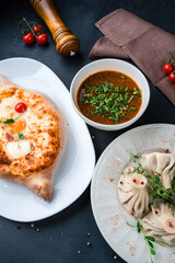 Georgian lunch khachapuri with egg, cherry tomato, butter and cheese, manti with meat and beef kharcho soup.