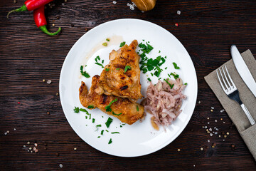 Fried chicken wings with onions and greens in plate.