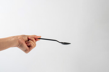 Black plastic spoon in hand on white background