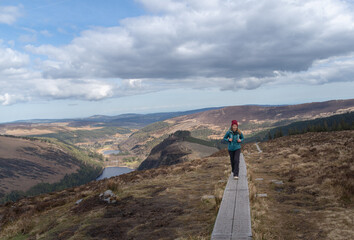 free and happy mountaineer woman walks on wooden walkway in national park wicklow mountains ireland