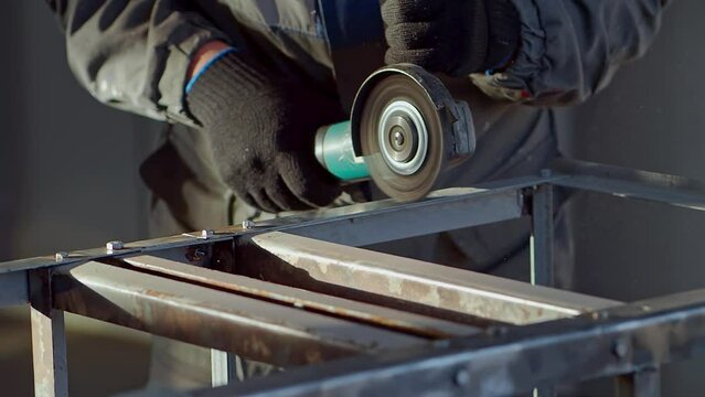 Mechanic works with angle grinder and cleans metal from old paint. Slow-motion close-up video. Worker's hands with tool. Preparing metal for painting. Anti-corrosion treatment.