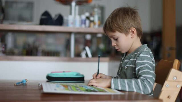 Child, school boy, writing homework at home after school.