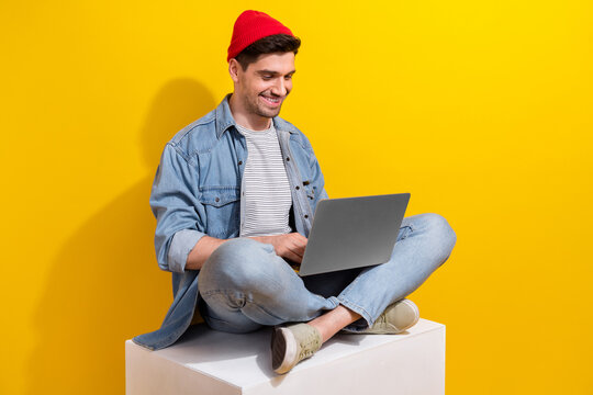 Photo of good mood cool man dressed jeans shirt working modern gadget empty space isolated yellow color background