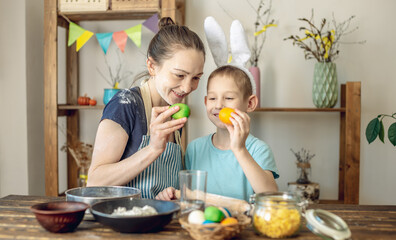 Obraz premium Happy Easter with your family. Mom and son are preparing for spring Easter by cheerfully coloring holiday eggs