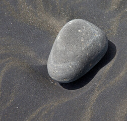Fototapeta na wymiar Stone in black sand at the beach. Mana Bay New Zealand. Patea. Taranaki. Tasman Sea. 