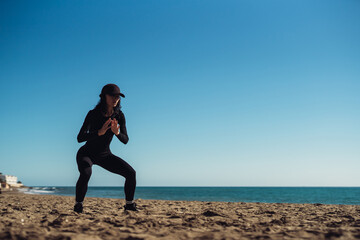 a girl doing exercises on the seashore in sportswear. fitness trainer girl doing exercise. There is...