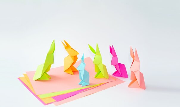 Spring, Easter holiday. Children's craft rabbit made of multi-colored paper on a bright colored background. The concept of children's creativity, origami, Easter mood. Front view