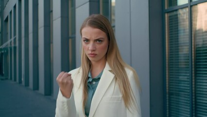Angry annoyed dissatisfied Caucasian woman businesswoman business lady leader boss female customer unhappy client outdoors near office building threaten looking camera shaking fist gesture aggression