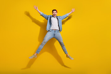 Full length photo of excited good mood guy wear denim jacket jumping high like star isolated yellow...
