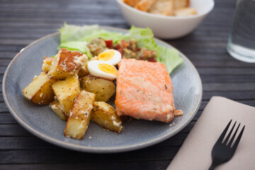 Baked salmon fillet with fried potato wedges, homemade guacamole and quail eggs halves