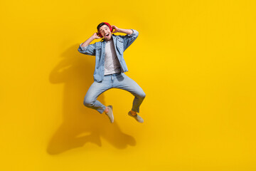 Fototapeta na wymiar Full length photo of funky impressed guy wear denim jacket jumping high enjoying songs empty space isolated yellow color background