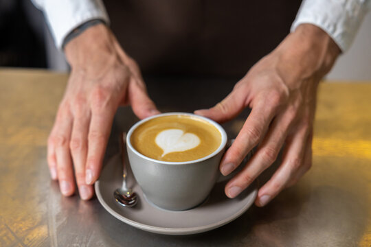 Picture of mans hands putting cup of coffee on the table