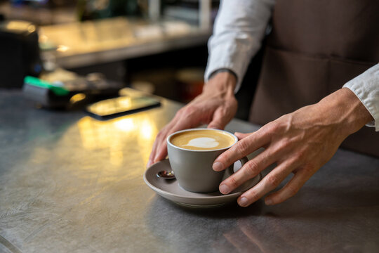Picture of mans hands putting cup of coffee on the table