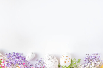 Happy Easter greeting card background with easter eggs and spring flowers. Easter holiday flat lay composition with copy space for text
