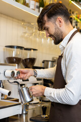 Smiling barista standing near coffee machine and looking contented
