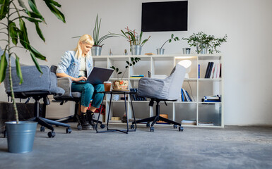 Young women sitting in coworking space working while using laptop.