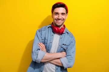 Photo of funky confident man dressed jeans shirt arms folded listening song earphones isolated yellow color background