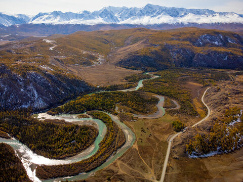 Breathtaking aerial shot of the winding Katun River amidst the majestic Altai Mountains landscape during autumn.
