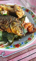a plate of simple Indonesian food, fried fish, fried chicken, chili sauce and fresh vegetables