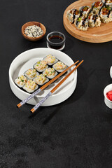 Assorted Sushi Rolls with Shrimp Tartare, Avocado, and Tobiko Caviar on a Modern Dark Surface