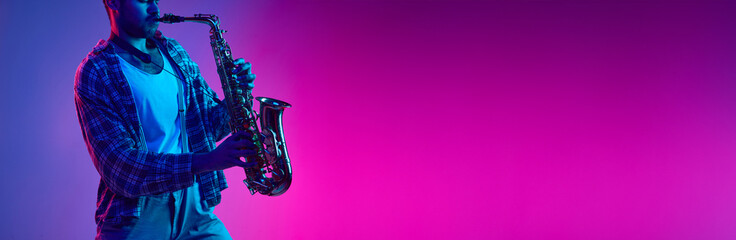 Banner. Jazzman playing on saxophone in neon light against gradient blue-pink background with...