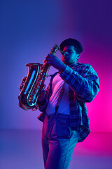 Naklejka premium Jazz musician in retro outfit virtuously playing saxophone against gradient blue-pink background in neon light. Concept of blues, classy instrumental music, festivals and concerts. Ad