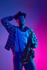 Joy of music. Modern musician, holds wind instrument, saxophone against gradient purple-pink...