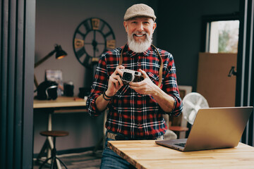 Portrait d'un homme photographe hipster situé dans un studio atelier et qui tient un appareil...