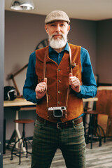 Portrait d'un homme photographe chic hipster élégant et stylé qui porte un appareril photo vintage argentique dans un atelier créatif