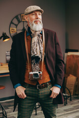 Portrait d'un photographe créatif et original  de type hispter très élégant et stylé avec un manteau un béret et un gilet dans un atelier créatif