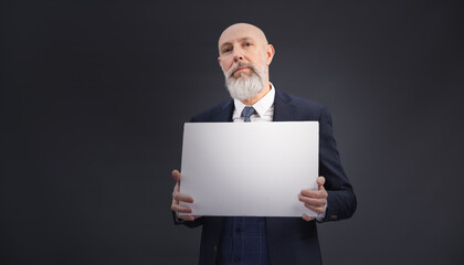 Portrait corporate d'un homme d'affaires désabusé en costume et avec barbe qui tient un panneau affiche blanc