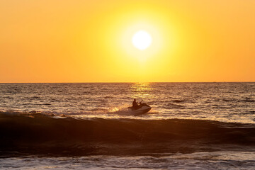 Beach lifeguard driving jet ski at sundown, Zicatela, Oaxaca, Mexico