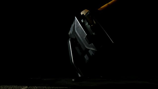 Blow of a big hammer to a computer monitor, isolated on a black background, steady slow motion shot. Technology, innovation, and destruction concepts.