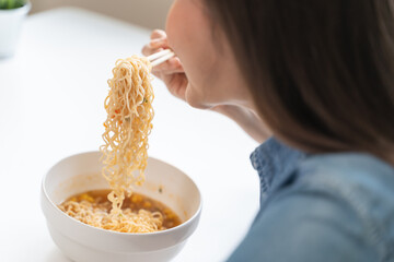 Young female eating instant noodle isolated on background.