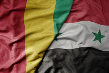 big waving national colorful flag of syria and national flag of guinea .