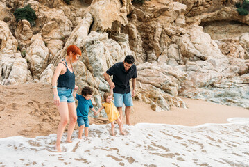 Happy family with kids standing on sandy seashore