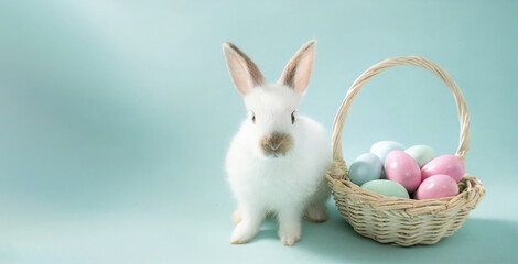 Easter bunny and basket of colorful eggs on pastel blue background