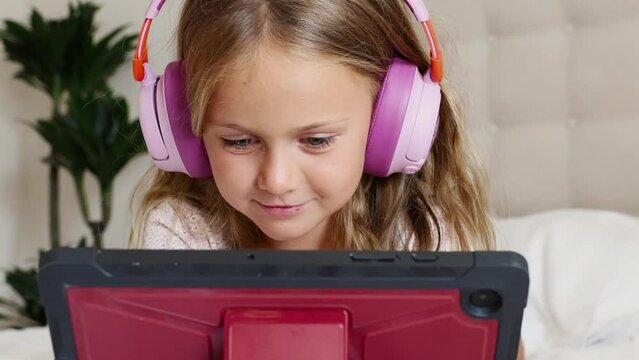 Emotion excited surprise child in headphones playing digital tablet computer home. Application for children development. Toddler watch interesting learning video, movie, online class, listen to music