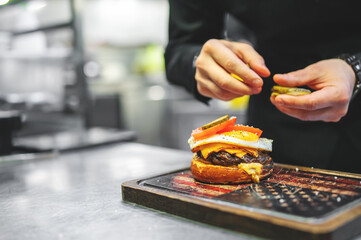 chef hand cooking cheese burger on restaurant kitchen