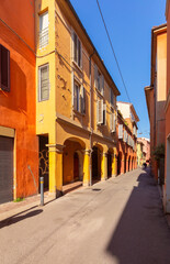 Bright multi-colored facades of old houses on a narrow street in Bologna.