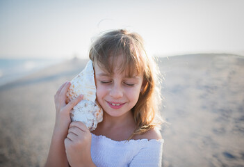 Cute little girl with sea shell on beach.