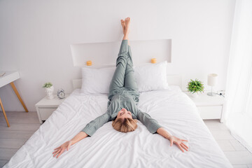 Photo of young beautiful happy blonde lady sleepy lying down white bed legs upside enjoy comfort at...