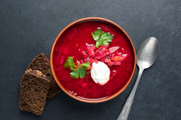 Red beet vegetarian soup Borscht served with sour cream in ceramic bowl, table top view