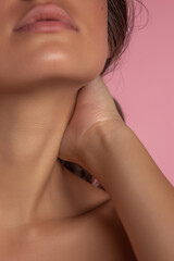 extreme close-up of woman's neck and lips against pink background