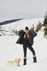 Fototapeta na wymiar Woman with dog enjoying snowy mountain landscape.
